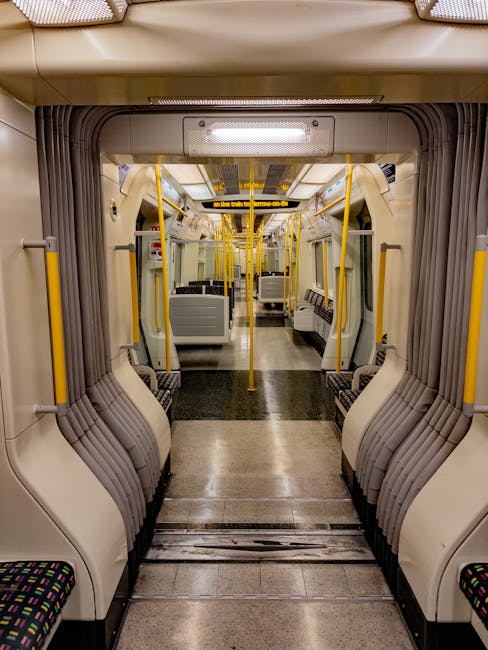 Close-up view of the London Underground platform at Stockwell station, showing a tiled beige wall with framed posters and digital displays, beneath a ceiling with fluorescent lights. A moving train wi